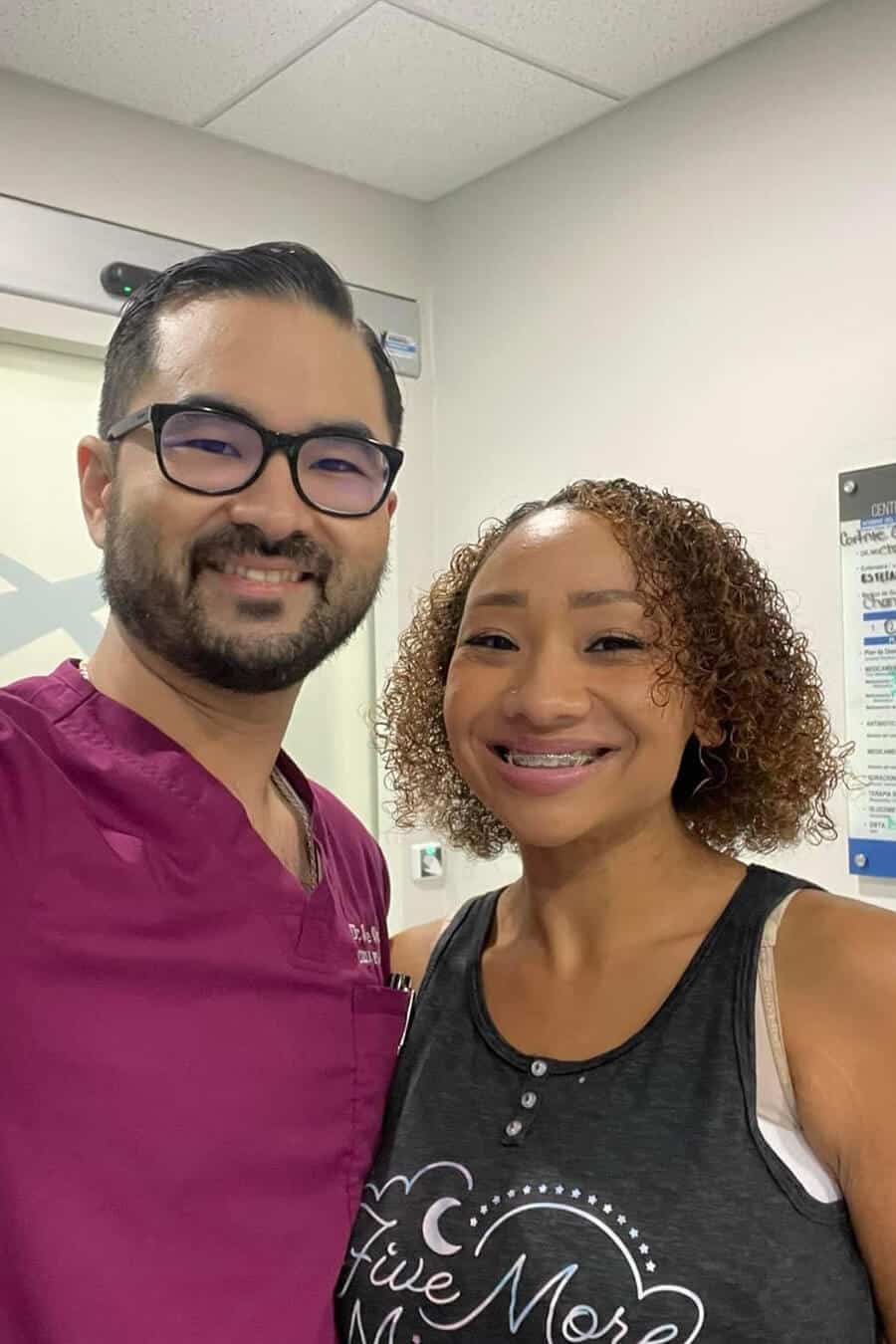 A smiling man and woman, both wearing glasses, posing together in a friendly setting.
