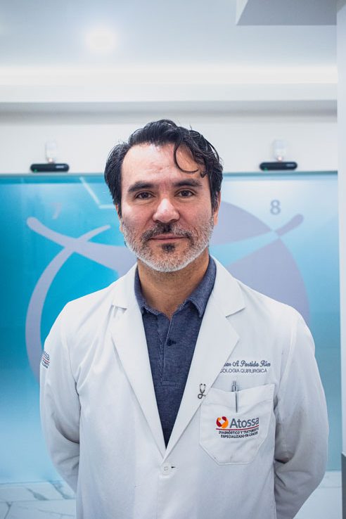 Doctor in a white lab coat standing and smiling in a medical office, with medical symbols on the frosted glass background.